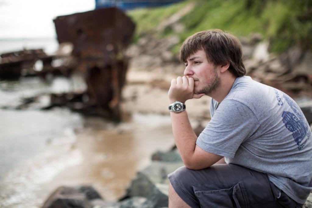 Young person stares contemplatively out at sea
